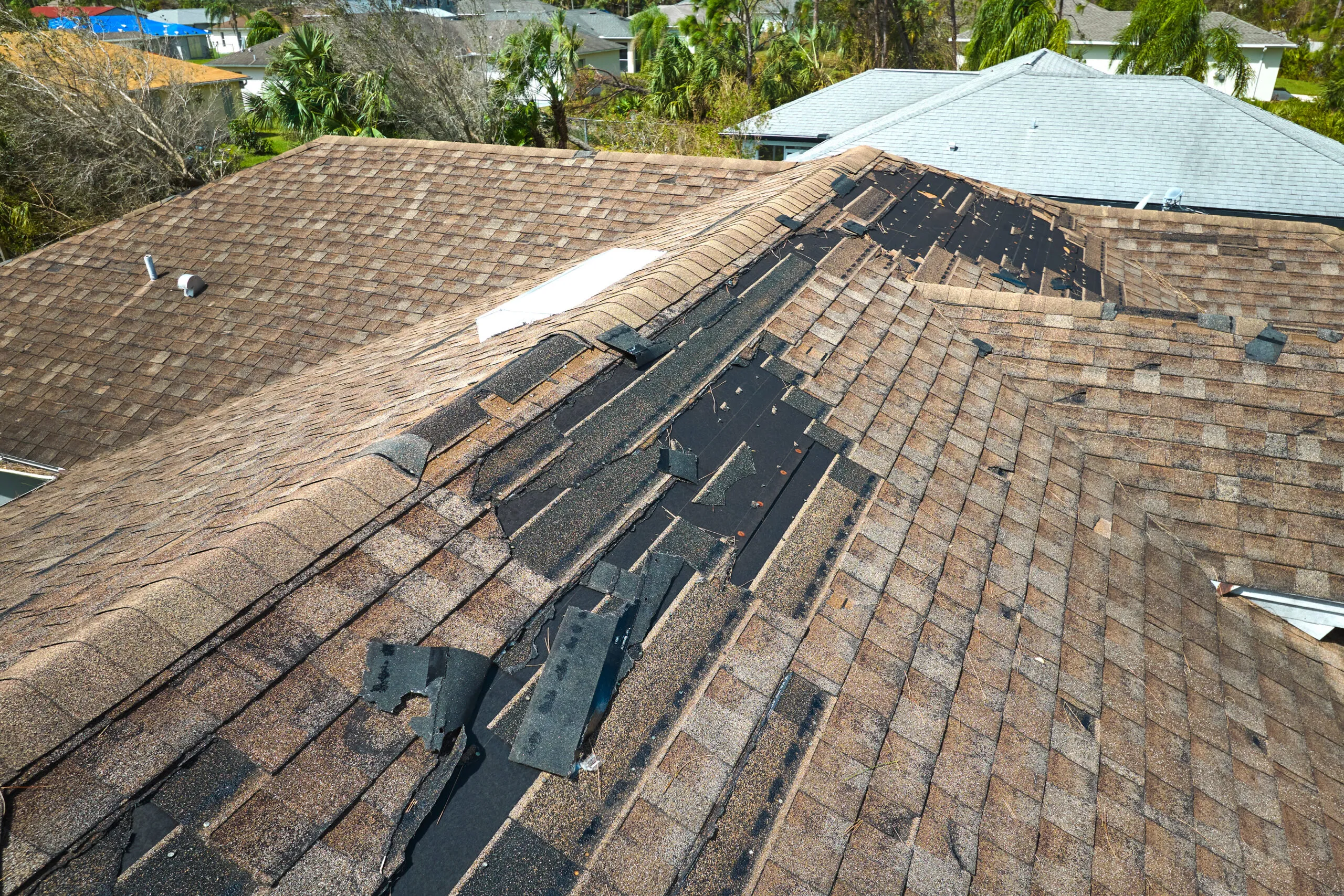 Damaged house roof with missing shingles after hurricane Ian in Florida. Consequences of natural disaster