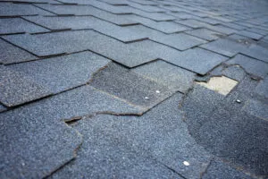 Close up view of bitumen shingles roof damage that needs repair.
