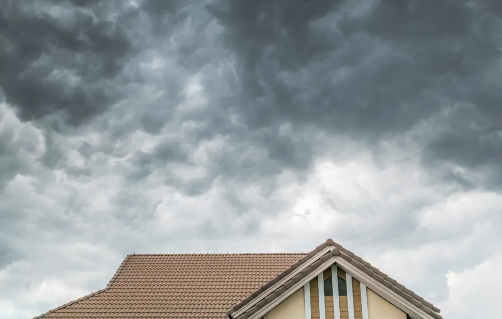 Dark clouds going to heavy rain over the house roof.